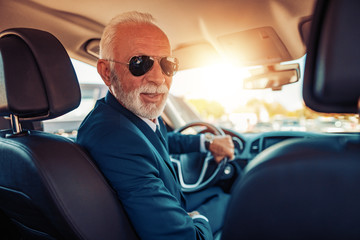 Confident senior businessman driving  car