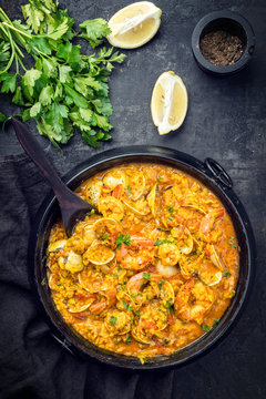 Traditional Portuguese arroz caldoso con almejas with shrimps and calm as top view in a cast-iron pot