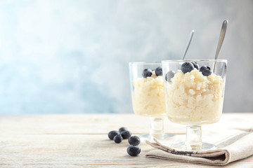 Creamy rice pudding with blueberries in dessert bowls on table. Space for text