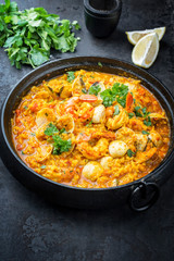 Traditional Portuguese arroz caldoso con almejas with shrimps and calm as closeup in a cast-iron pot