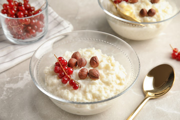Creamy rice pudding with red currant and hazelnuts in bowls served on grey table