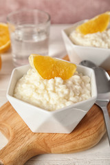 Creamy rice pudding with orange served on wooden table