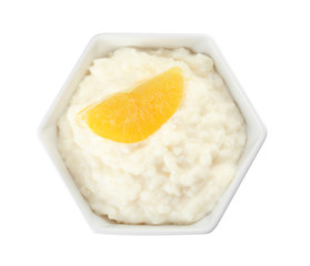 Creamy rice pudding with orange slice in bowl on white background, top view