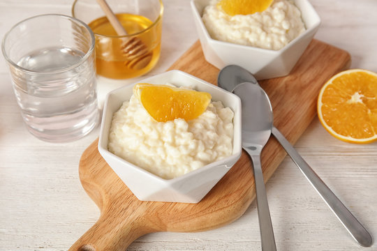 Creamy rice pudding with orange slices in bowls served on wooden table