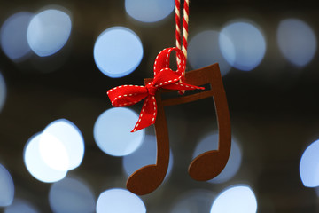 Wooden music notes against blurred Christmas lights