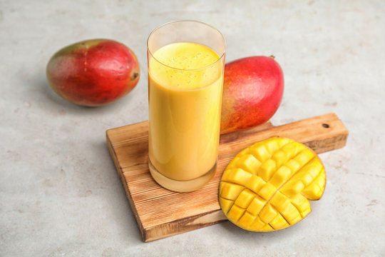 Glass of fresh mango drink and fruits on table