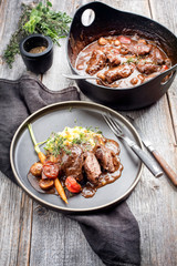 Traditionell geschmorte deutsche Schweinebäckchen in brauner Rotwein Sauce mit Pilzen und Kartoffelpüree als closeup auf einem Modern Design Teller