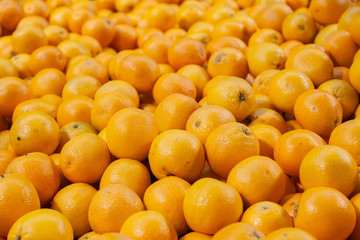 Many ripe orange mandarins are piled on the counter at the farmers market. New Year fruit concept, fresh squeezed vitamin juice, healthy foods