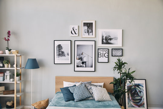 photos of different sizes in a frame hanging over the bed . Modern bedroom interior.