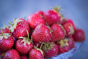Ripe strawberries in  glass plate on  gray wooden background.