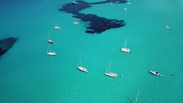 Amazing drone aerial landscape of the charming beach Es Trencs and the boats with a turquoise sea. It has earned the reputation of Caribbean beach of Mallorca. Spain