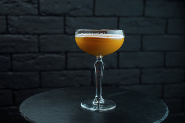 Orange delicious sweet cocktail with tonic and vodka with sweet syrup in restaurant on wooden table...
