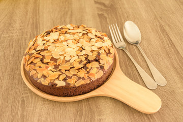 Brownie with almond on wood plate.