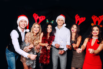 Party with friends. They love Christmas. Group of cheerful young people carrying sparklers and champagne flutes dancing in new year party and looking happy. Concepts about togetherness lifestyle