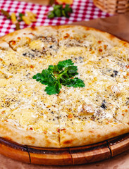 Italian Pizza four cheese (quattro fromaggi) on wooden cutting board. Close up