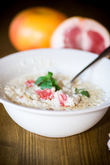 sweet oatmeal with slices of red grapefruit in a ceramic bowl