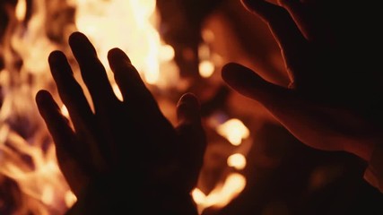 Man rubbing hands in front of burning fireplace home hot wood burning cozy relax season relaxation temperature romantic night close up slow motion