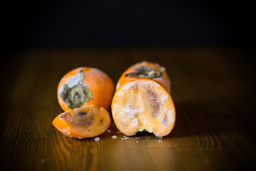frozen ripe persimmon in ice on wooden