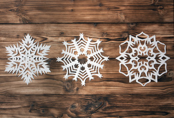 snowflakes cut out of paper on a wooden background