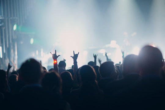 Concert, event or party concept. People with hands up at the scene, spotlight, colored light.
