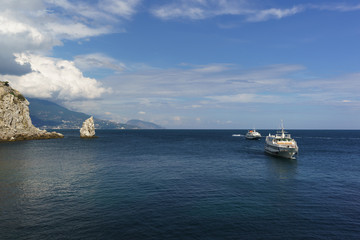 Obraz premium Two white ships sail the calm blue sea on a Sunny day. Cape Limen-Burun and rock Sail in the black sea resort of Crimea