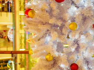 Fototapeta na wymiar Closeup of ornament balls and lights on a white christmas tree at a department store. Shallow focus. Bangkok, Thailand. Travel and holidays concept.
