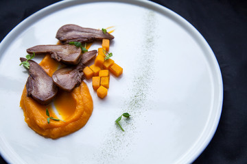 beef tongue cut into pieces with pieces of orange pumpkin lies on a white plate