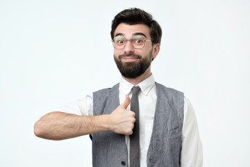 Yeah I like it concept. Pleased and satisfied male in glasses raising thumbs up and smiling broadly, giving positive feedback about party club