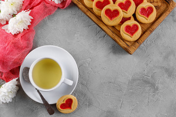 Flat lay. Cup with green tea and cookies with a heart on a decorative board. Valentine's day concept. Space under the text.