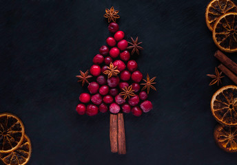 Christmas tree from frozen cherries, cinnamon sticks and star anise, on dark background. Christmas...