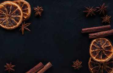 Christmas frame with dried oranges, star anise and cinnamon sticks on dark background. Top view, copy space