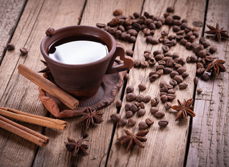 coffee beans in jute bag with coffee grinder and hot cup of coffee on wooden table