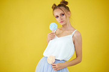 young girl with candy on a yellow bright background. beautiful make-up,