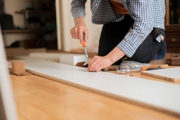 person installing new furniture in his accomodation on wooden floor а