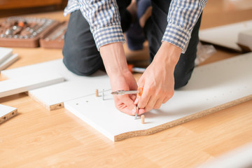 close up man assembling new furniture with a screwdriver b