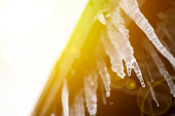 spring season begin, sunny sky and icicles hang from roof ledge and melting f