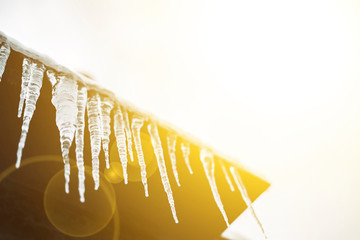spring season begin, sunny sky and icicles hang from roof ledge and melting f