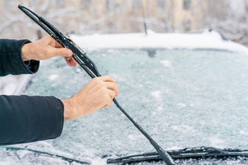man adjusting and cleaning wipers of car in snowy weather b - obrazy, fototapety, plakaty
