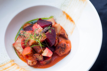 beet salad with vegetables in a white plate on a black background