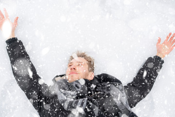 young man covered in snow lying on the ground in snowfall z