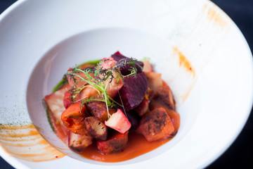 beet salad with vegetables in a white plate on a black background