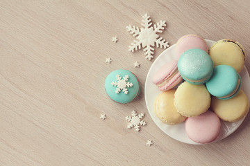 Cakes macaroons in winter Christmas design. Cookies with snowflakes on wooden background. Christmas background.