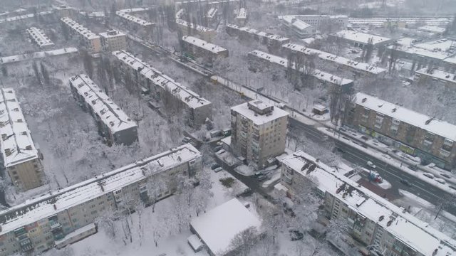 Aerial view. The drone flies above typical residential area at Eastern Europe. The drone flies during the snowfall. Kiev, Ukraine. 4K.