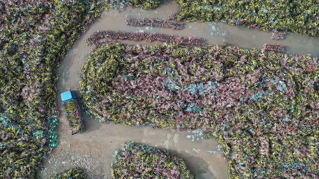 Overhead drone shot of a truck bringing confiscated rental bicycles to a large dumping ground in Shanghai, China