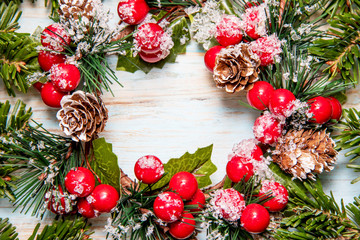 Beautiful frame from green branches of a Christmas tree with traditional Christmas wreath on a blue board with a place for the inscription