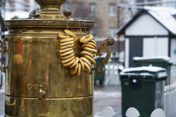 Big copper samovar, for preparation of tea, fresh tasty donuts hang on its pen