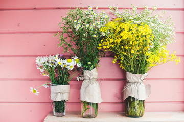  Home decor. Wildflowers in a vase on a background of wooden pink boards.
