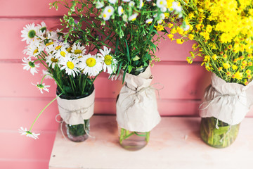 Home decor. Wildflowers in a vase on a background of wooden pink boards.	