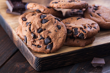 Homemade chocolate cookies on dark old wooden table. Chocolate chips cookies shot.