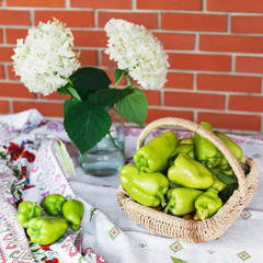 Vegetables in the basket on the table. Autumn harvest. Green pepper, and hydrangea in a vase.